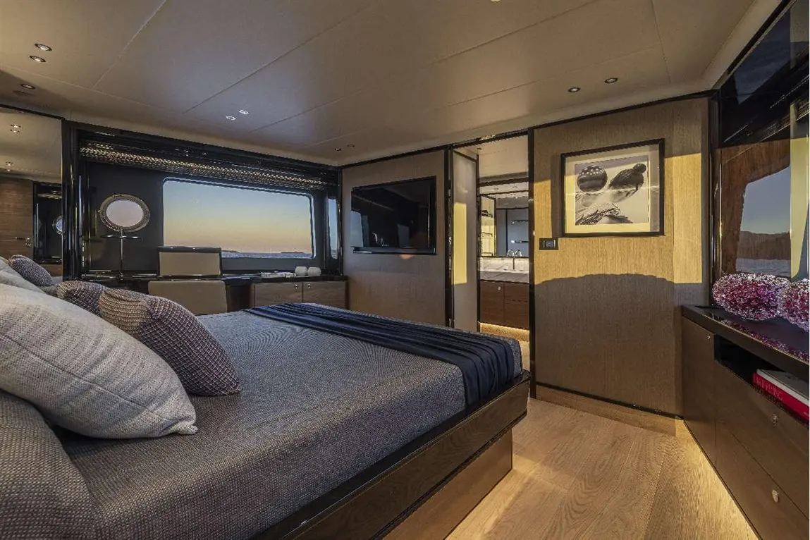 Luxurious bedroom in a yacht featuring a double bed, ocean view, modern furnishings, and an en-suite bathroom entrance.